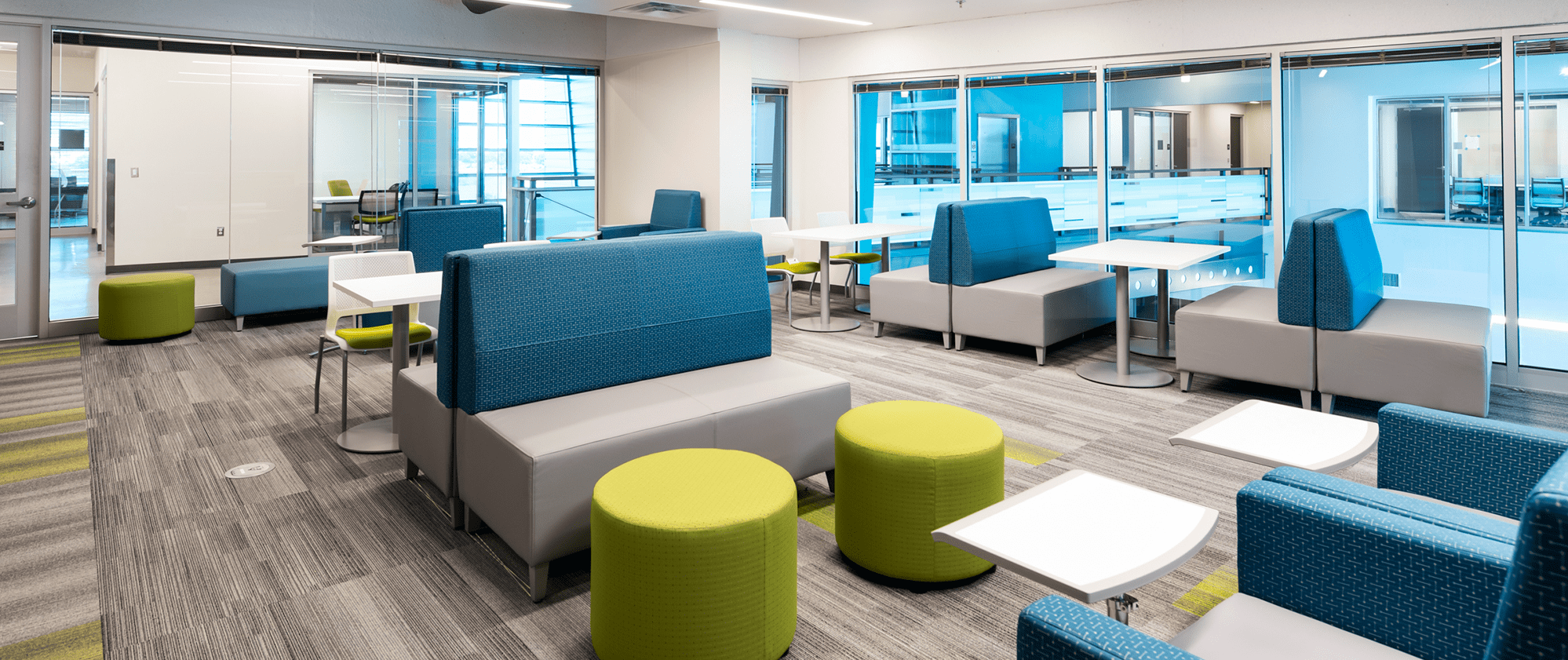 Student lobby with modern seating including tables, chairs and individual work stations.